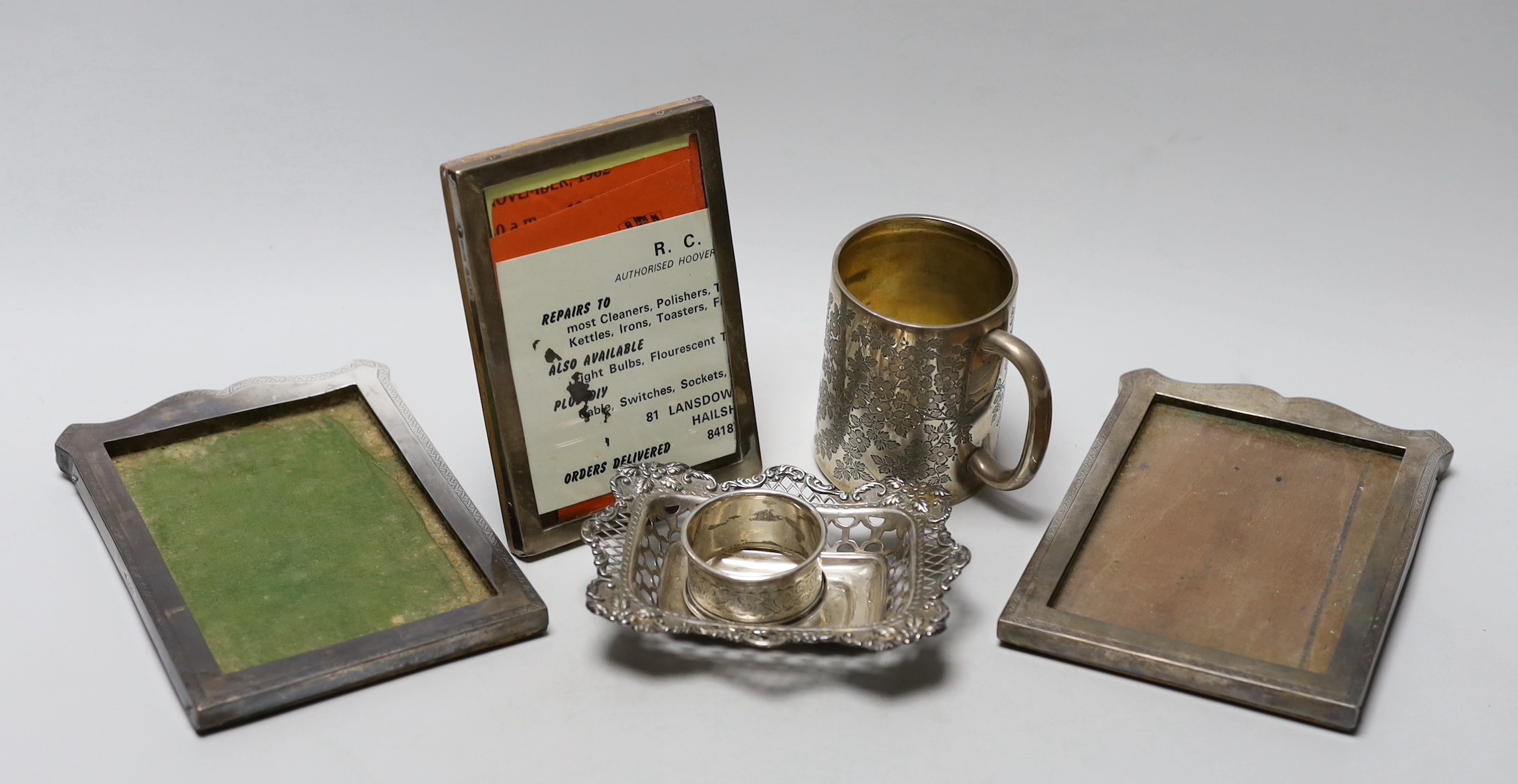 A Victorian engraved silver christening mug, London, 1890, 81mm, a silver napkin ring, a repousse silver dish and three silver mounted photograph frames.